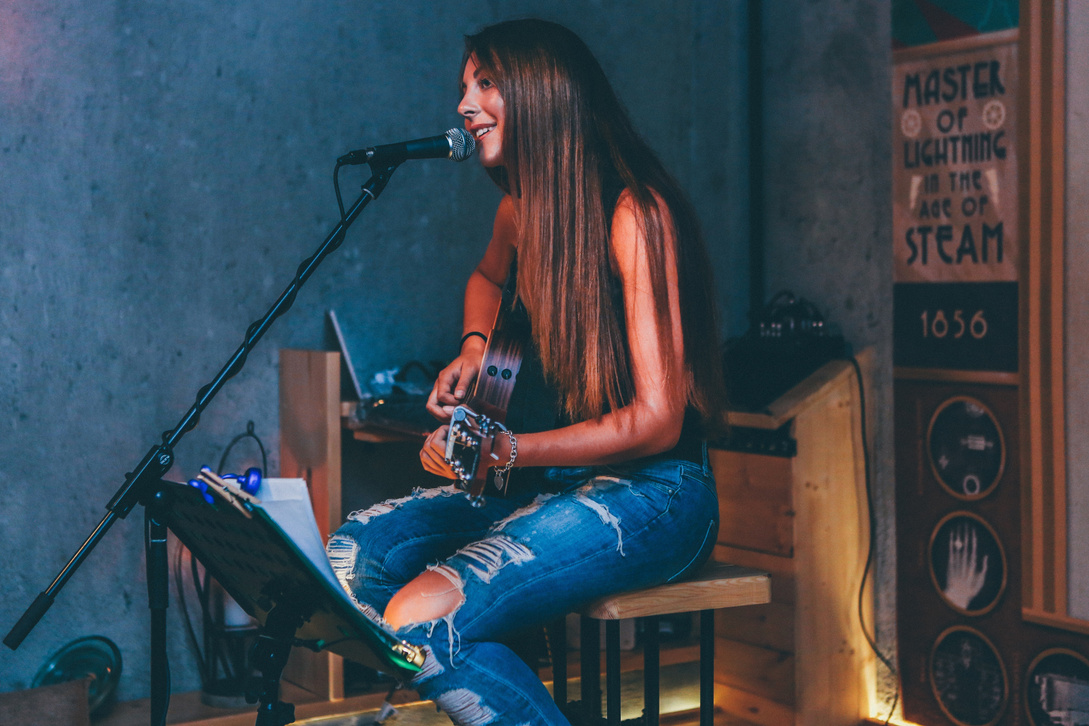 Woman Singing and Playing an Acoustic Guitar